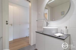een witte badkamer met een wastafel en een spiegel bij Home Azores - Coliseu Residences in Ponta Delgada