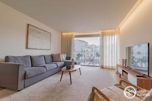 Sala de estar con sofá gris y TV en Home Azores - Coliseu Residences en Ponta Delgada