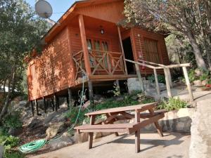 una casa de madera con un banco de picnic frente a ella en Cabañas Lomas del Manzano, en San José de Maipo