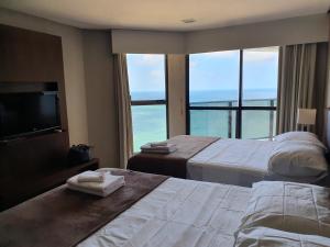 a hotel room with two beds and a view of the ocean at Flat Beach Class Internacional in Recife +30 photos