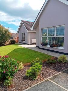a house with a yard with grass and flowers at Mary's place in Castlewellan