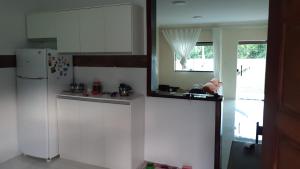 cocina con armarios blancos y nevera blanca en Casa condominio Rancho de Jacone en Maricá