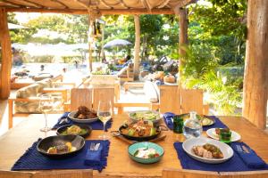 a wooden table with plates of food and glasses of wine at Blue Apple Beach in Tierra Bomba