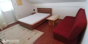 a small bedroom with a bed and a red chair at Apartments with a parking space Sveti Petar, Biograd - 3251 in Sveti Filip i Jakov