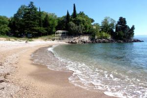 a sandy beach with water and trees in the background at Apartments with parking space Lovran, Opatija - 7705 in Lovran