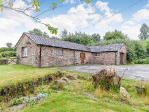 an old stone house with a driveway in a field at Foxlair Cottage in Withypool