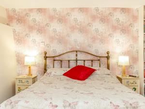 a bedroom with a bed with a red pillow on it at Foxlair Cottage in Withypool