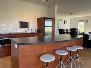 a kitchen with a counter with stools around it at Kangaroo Pause Holiday home at Clayton Bay in Clayton Bay