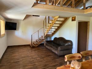 - un salon avec un canapé en cuir et des escaliers dans l'établissement Cabañas el Pino 3, à Creel