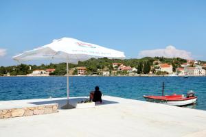 a person sitting on a dock under an umbrella at Twin Room Luka 8132e in Žman