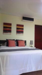 um quarto com uma cama branca e almofadas vermelhas em D9 Casa de Huespedes em Santo Domingo