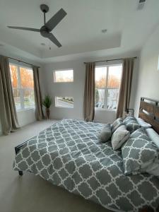 a bedroom with a bed with a gray comforter and windows at Entire Home Close to BOA Stadium & City in Charlotte