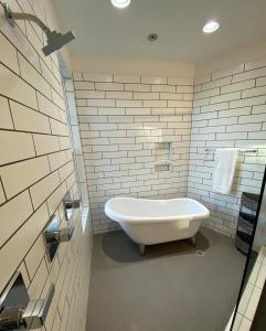 uma banheira branca na casa de banho com tijolos brancos em Entire Home Close to BOA Stadium & City em Charlotte