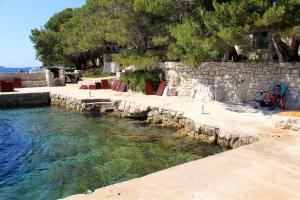 een zwembad met water naast een stenen muur bij Secluded fisherman's cottage Lavdara, Dugi otok - 8155 in Sali