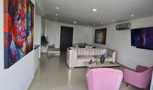 uma sala de estar com um sofá branco e cadeiras cor-de-rosa em Espectacular Penthouse dúplex bien equipado em Barranquilla