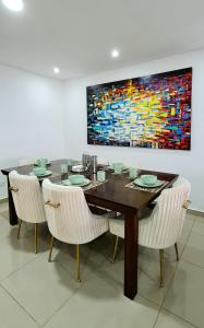 un comedor con mesa, sillas y una pintura en Espectacular Penthouse dúplex bien equipado, en Barranquilla