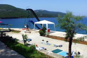 un parque infantil con un tobogán junto al agua en Apartments by the sea Luka, Dugi otok - 8182, en Luka