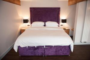 a bedroom with a large bed with a purple headboard at Hotel Forty One in Great Driffield