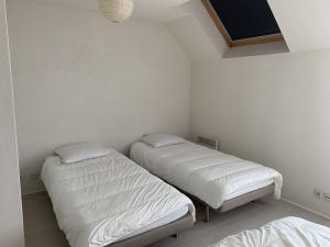 two beds in a room with white walls at Appartement Dives-sur-Mer, 2 pièces, 4 personnes - FR-1-487-236 in Dives-sur-Mer