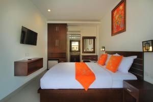 een slaapkamer met een groot wit bed met oranje kussens bij Lotus Tirta Seminyak in Seminyak