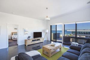 a living room with a couch and a tv at Mollymook Luxury Beachfront Apartment 10 in Mollymook