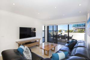 a living room with a couch and a television at Beachfront 2 in Mollymook