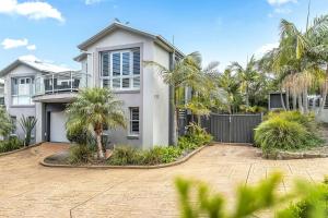 una casa blanca con una valla y palmeras en North Harbour, en Ulladulla