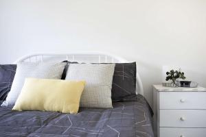 a bed with gray and white pillows and a white night stand at Fathoms 3 Ocean Breeze in Mollymook