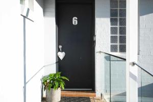 a black door with a heart on it with a plant at Mariners 6 in Mollymook