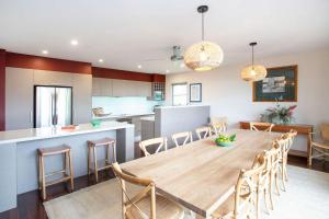 a dining room and kitchen with a wooden table and chairs at Aurora in Mollymook