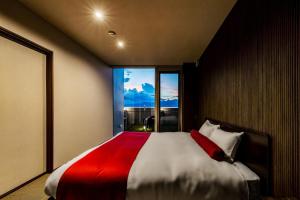天草三角シーサイドヴィラ في Uki: غرفة نوم بسرير كبير مع بطانية حمراء