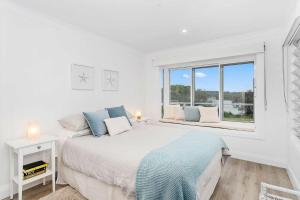 a white bedroom with a large bed and a window at SurfBreak on Seaside in Burrill Lake