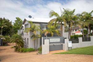 uma casa branca com palmeiras em frente em Harbour Haven em Ulladulla