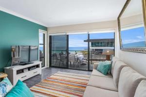 a living room with a couch and a television at Beachfront Five in Mollymook