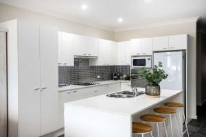 a white kitchen with a sink and a counter at Beachfront Five in Mollymook