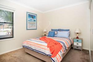 a bedroom with a bed and a window at Beachfront Five in Mollymook