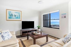 a living room with a couch and a tv at Beachfront Six in Mollymook