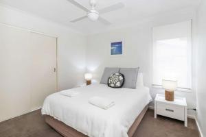 a white bedroom with a bed and a white ceiling at Beachfront Six in Mollymook