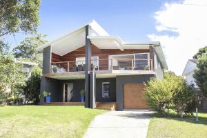 a modern house with a balcony and a yard at Ocean Blue in Ulladulla
