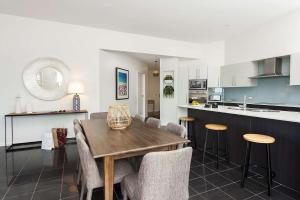 a kitchen and dining room with a wooden table and chairs at The Penthouse in Mollymook