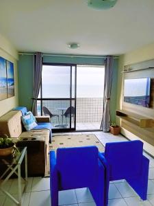 a living room with blue chairs and a view of the ocean at Conforto e melhor vista - 100 metros da praia in Natal
