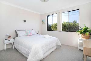 Un dormitorio blanco con una cama y una ventana. en Surfmist One on Mollymook, en Mollymook