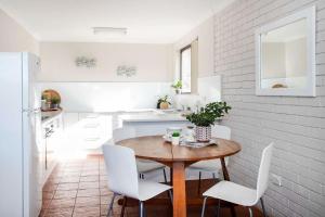 cocina y comedor con mesa de madera y sillas blancas en Surfmist One on Mollymook, en Mollymook 7 fotos más