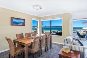 a dining room with a table and chairs and a couch at Beachfront Four in Mollymook