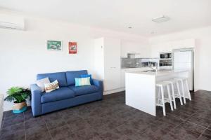 a living room with a blue couch and a kitchen at Beachfront Four in Mollymook +12 photos