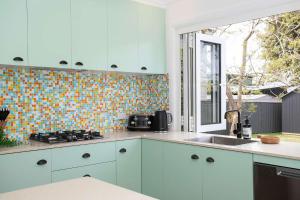 a kitchen with blue cabinets and a tile wall at Villa Marie in Narrawallee