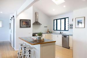 a kitchen with white cabinets and a counter with stools at Northstar on Mollymook Beach in Mollymook