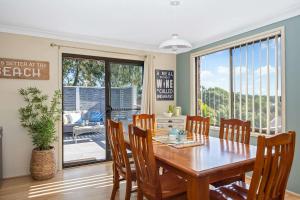 a dining room with a wooden table and chairs at Narrawallee Retreat in Narrawallee