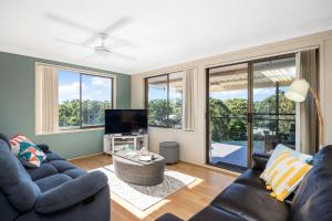 a living room with a couch and a tv at Narrawallee Retreat in Narrawallee