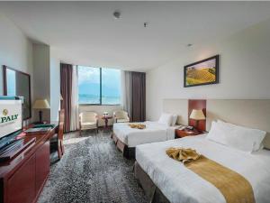 a hotel room with two beds and a flat screen tv at Sapaly Lao Cai City Hotel in Lao Cai